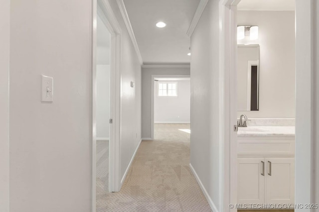 hall featuring ornamental molding, sink, and light colored carpet