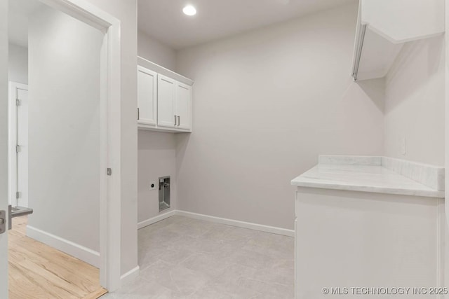 laundry room with electric dryer hookup and cabinets