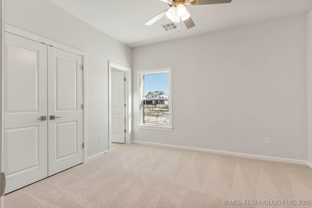 unfurnished bedroom featuring ceiling fan, light colored carpet, and a closet