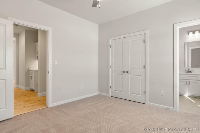 unfurnished bedroom with sink, ensuite bath, light carpet, a closet, and ceiling fan