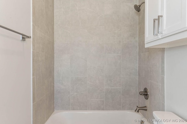 bathroom featuring tiled shower / bath combo and toilet