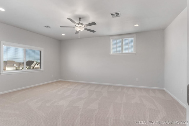 spare room with visible vents, a ceiling fan, baseboards, and light carpet