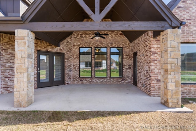 doorway to property featuring brick siding, board and batten siding, french doors, a ceiling fan, and a patio