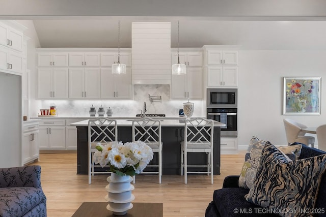 kitchen featuring built in microwave, stainless steel oven, white cabinets, and open floor plan