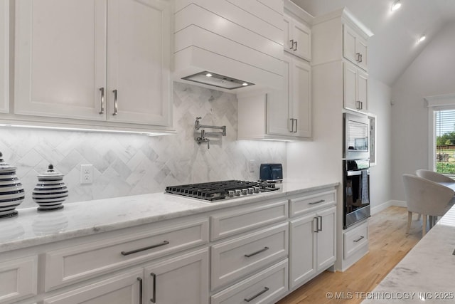 kitchen featuring light wood-style flooring, appliances with stainless steel finishes, backsplash, and white cabinets