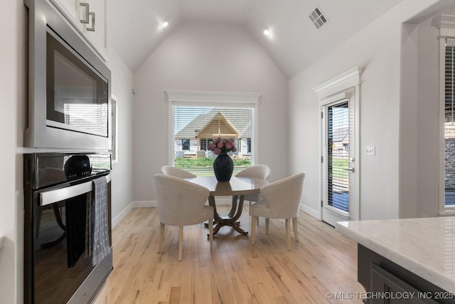 dining area with baseboards, visible vents, lofted ceiling, and light wood-type flooring