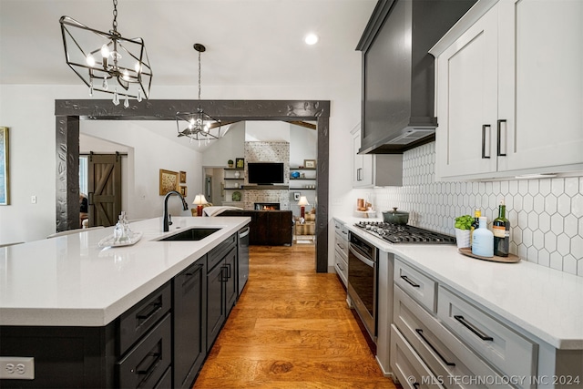 kitchen featuring light hardwood / wood-style floors, a center island with sink, stainless steel appliances, backsplash, and sink