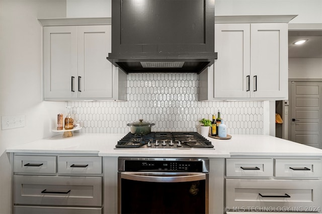 kitchen featuring appliances with stainless steel finishes, custom range hood, and tasteful backsplash