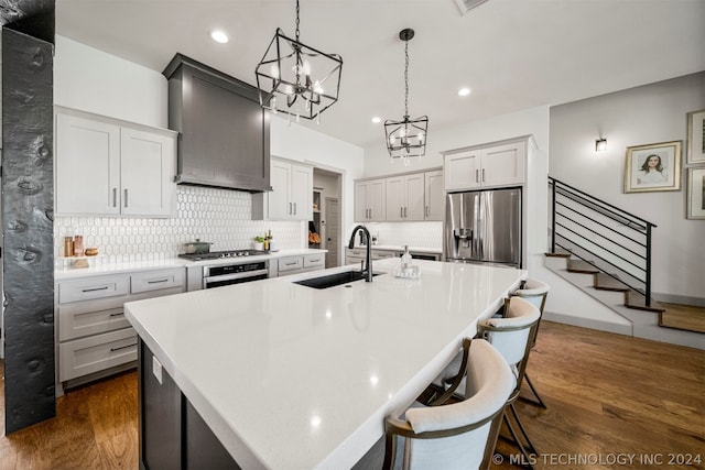 kitchen with appliances with stainless steel finishes, sink, dark wood-type flooring, and an island with sink