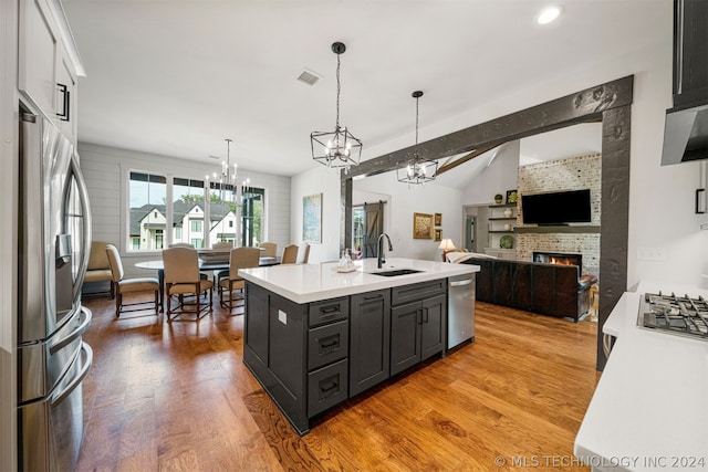 kitchen with wood-type flooring, an inviting chandelier, hanging light fixtures, sink, and appliances with stainless steel finishes