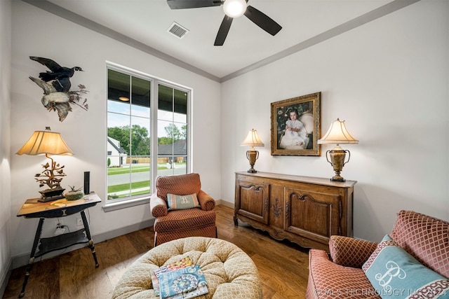 sitting room featuring a wealth of natural light, dark wood-type flooring, ornamental molding, and ceiling fan