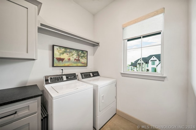 laundry area featuring washer and dryer, cabinets, and light tile flooring