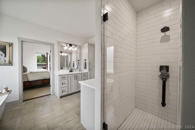 bathroom with a tile shower, vanity, and tile floors