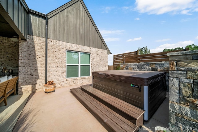 wooden deck with a hot tub and a patio