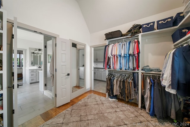 walk in closet featuring high vaulted ceiling, washer / clothes dryer, and light tile floors