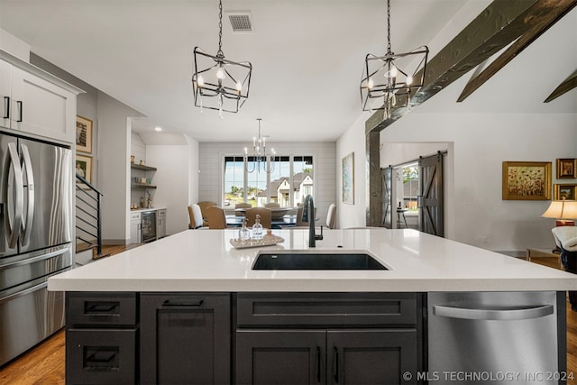 kitchen featuring hardwood / wood-style floors, white cabinetry, an island with sink, appliances with stainless steel finishes, and sink