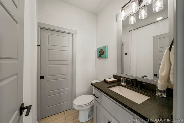 bathroom featuring tile flooring, vanity, and toilet