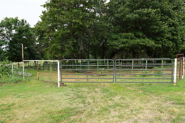 view of gate featuring a rural view and a lawn