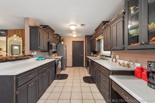 kitchen featuring appliances with stainless steel finishes, sink, dark brown cabinetry, and light tile patterned floors