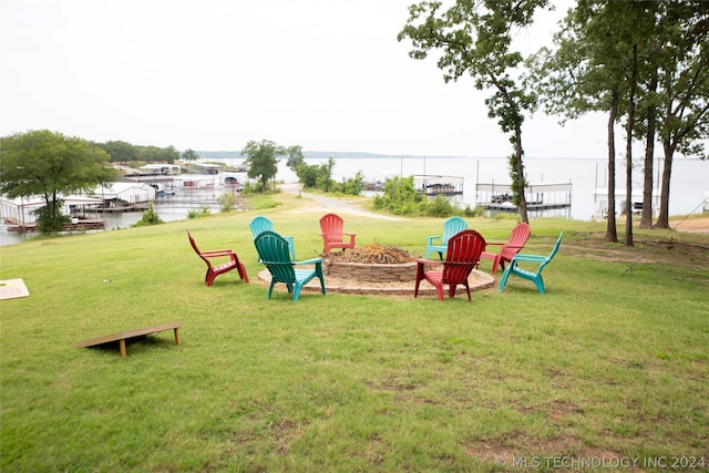 view of property's community with a water view, a lawn, and a fire pit