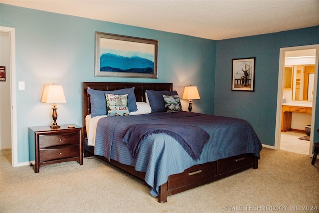 carpeted bedroom featuring ensuite bath and a textured ceiling