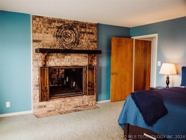 carpeted bedroom with a textured ceiling and a brick fireplace