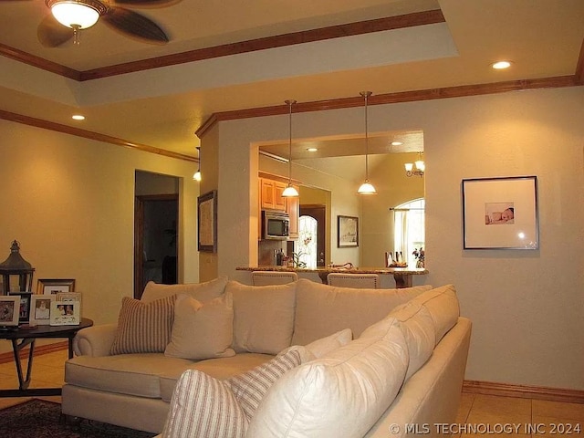 living room featuring light tile patterned floors, a raised ceiling, ceiling fan, and ornamental molding