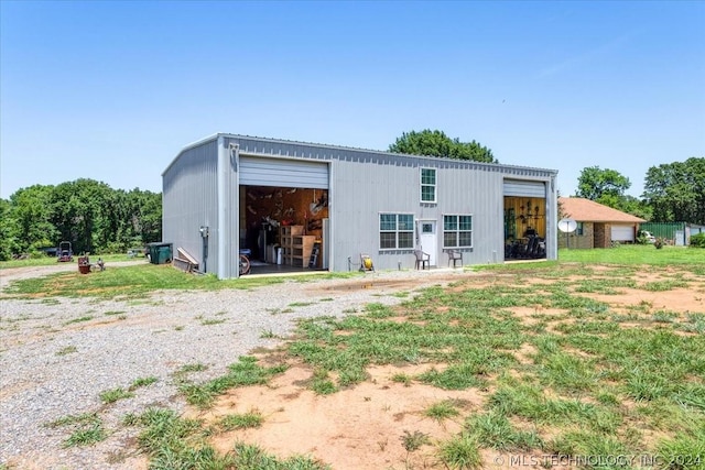 back of house featuring a garage and an outbuilding