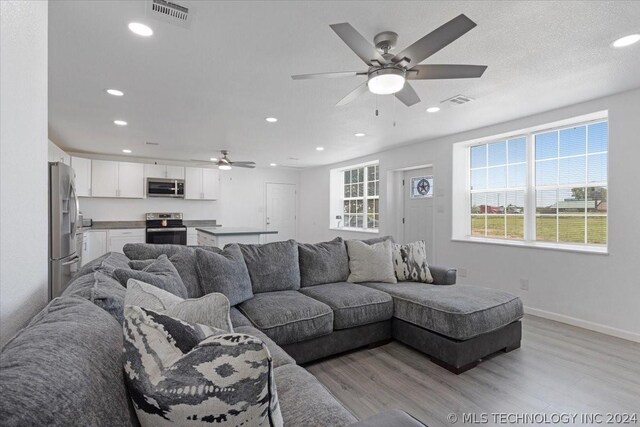 living area featuring visible vents, baseboards, a ceiling fan, light wood-style flooring, and recessed lighting