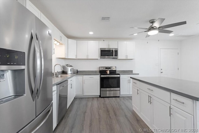 kitchen featuring visible vents, appliances with stainless steel finishes, wood finished floors, white cabinetry, and a sink