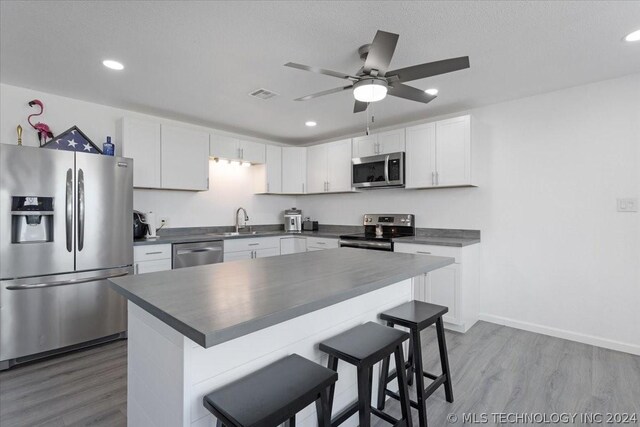 kitchen featuring visible vents, dark countertops, stainless steel appliances, white cabinetry, and a sink