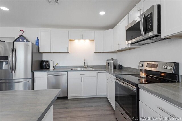 kitchen featuring dark countertops, appliances with stainless steel finishes, white cabinets, and a sink