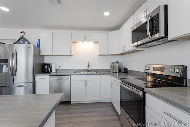 kitchen featuring a sink, stainless steel appliances, wood finished floors, and white cabinets
