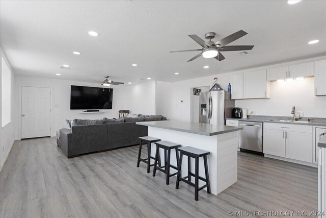 kitchen featuring white cabinetry, a kitchen island, appliances with stainless steel finishes, and a breakfast bar area