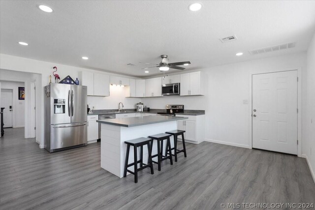 kitchen featuring wood finished floors, visible vents, white cabinetry, appliances with stainless steel finishes, and a center island