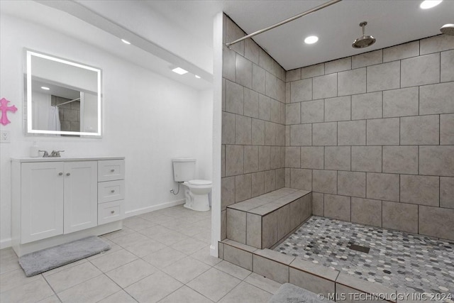 bathroom featuring vanity, baseboards, tiled shower, tile patterned flooring, and toilet
