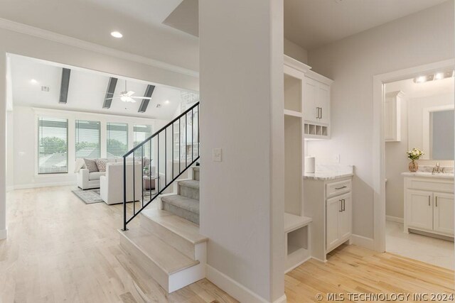 stairs with ceiling fan, hardwood / wood-style floors, beamed ceiling, and sink