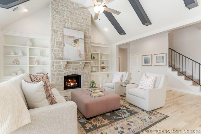 living room featuring a fireplace, high vaulted ceiling, built in shelves, light hardwood / wood-style flooring, and ceiling fan