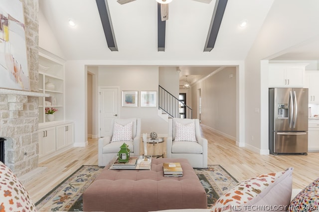 living room featuring light hardwood / wood-style flooring, ceiling fan, high vaulted ceiling, and a stone fireplace