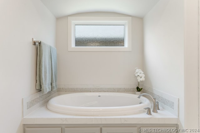 bathroom featuring vaulted ceiling and a bathtub