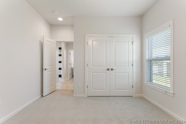 unfurnished bedroom featuring light carpet and a closet