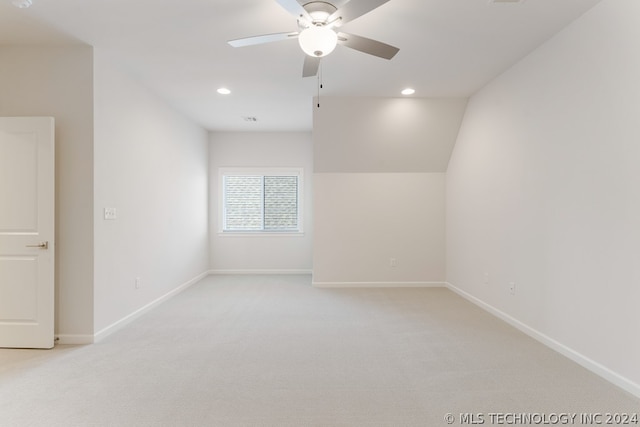 carpeted spare room featuring lofted ceiling and ceiling fan