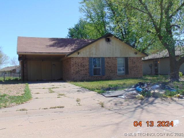 ranch-style home with concrete driveway, a carport, and brick siding