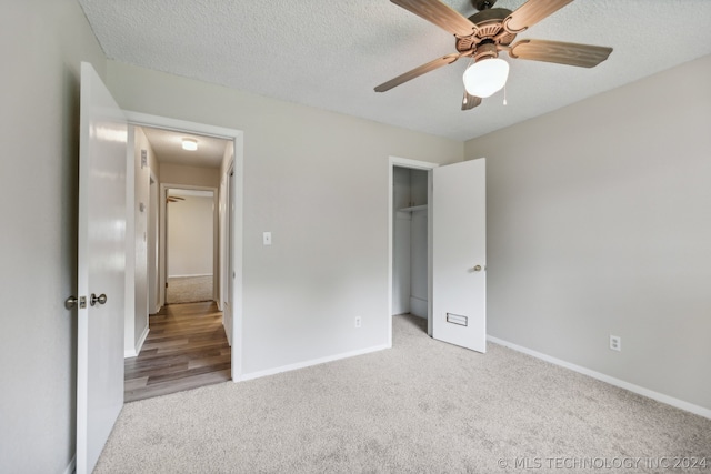 unfurnished bedroom with light colored carpet, a textured ceiling, ceiling fan, and a closet