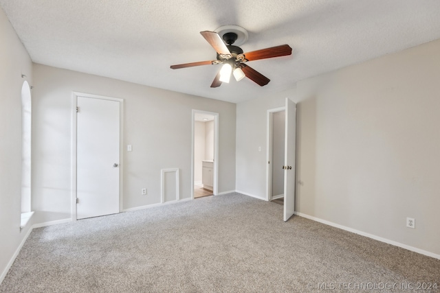 unfurnished bedroom with ceiling fan, ensuite bathroom, and a textured ceiling