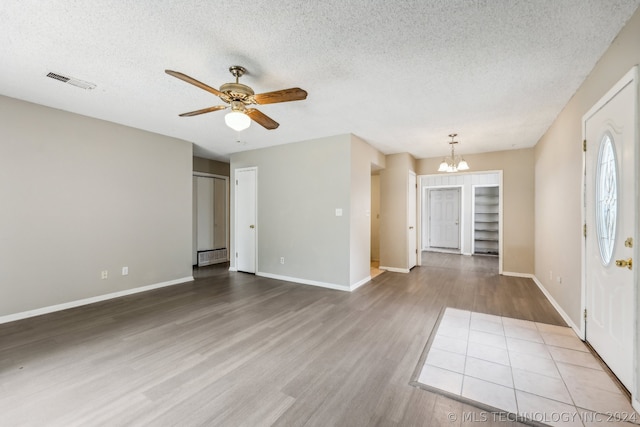 unfurnished room with hardwood / wood-style flooring, ceiling fan with notable chandelier, and a textured ceiling