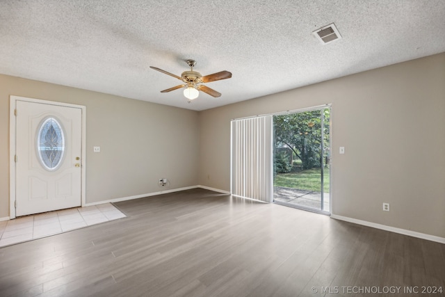 foyer with ceiling fan, a textured ceiling, and light wood-type flooring