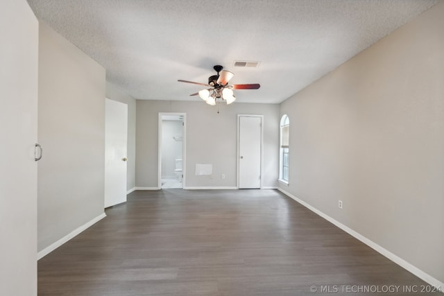 unfurnished room featuring ceiling fan, dark wood-type flooring, and a textured ceiling