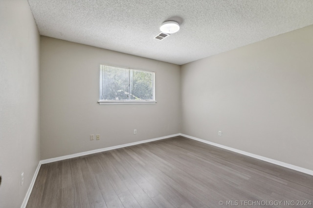 empty room featuring wood-type flooring and a textured ceiling