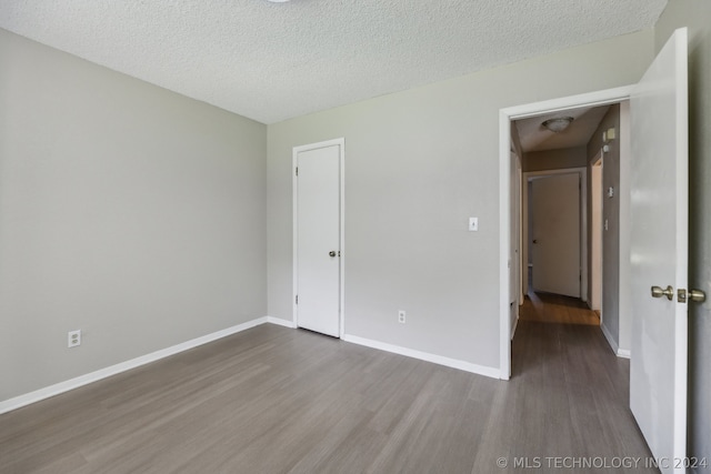 unfurnished bedroom with dark wood-type flooring and a textured ceiling